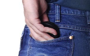 A person puts a round container in their back jeans pocket.