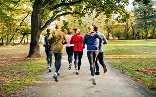 A rear view of joggers running through a park