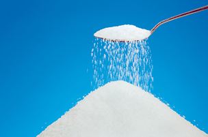 sugar falling from a spoon into a pile of sugar
