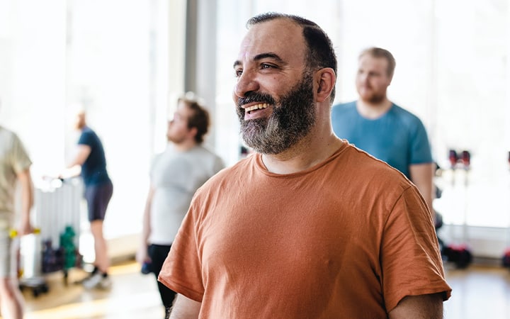 Smiling man looking away with male friends in background at exercise class