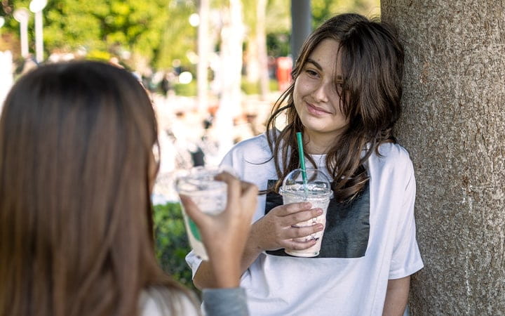 two teen girls drinking fancy coffee drinks