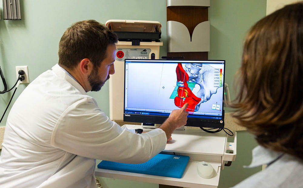 Dr. Brandon Jonard looking at a simulation of a 3D implant on a computer monitor