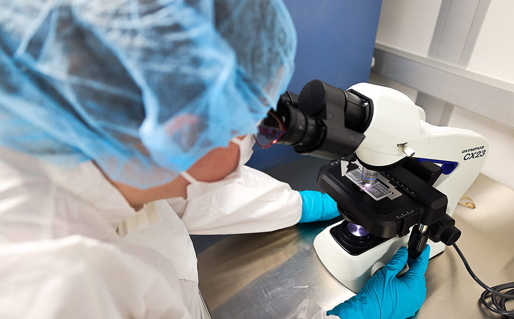 An immunotherapy technician looks through a microscope
