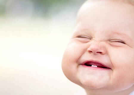 Baby smiling with one tooth showing.